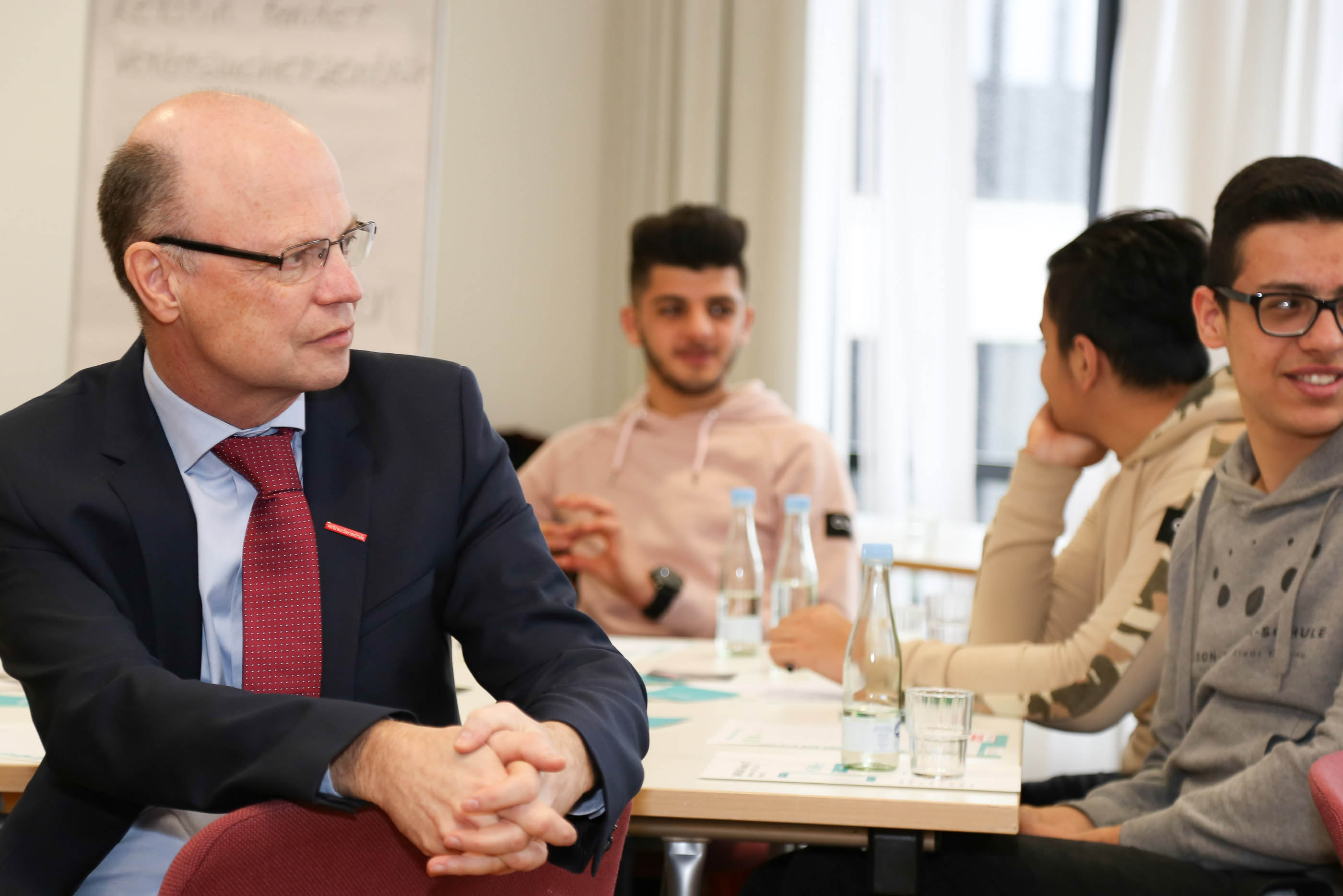 Wolfgang Schuldzinski, Vorstand der Verbraucherzentrale NRW, mit Teilnehmern des Kurses für geflüchtete junge Erwachsene „Smartphone und Kostenfallen“ des Projekts „Get in! - Integration geflüchteter Menschen in den Konsumentenalltag“