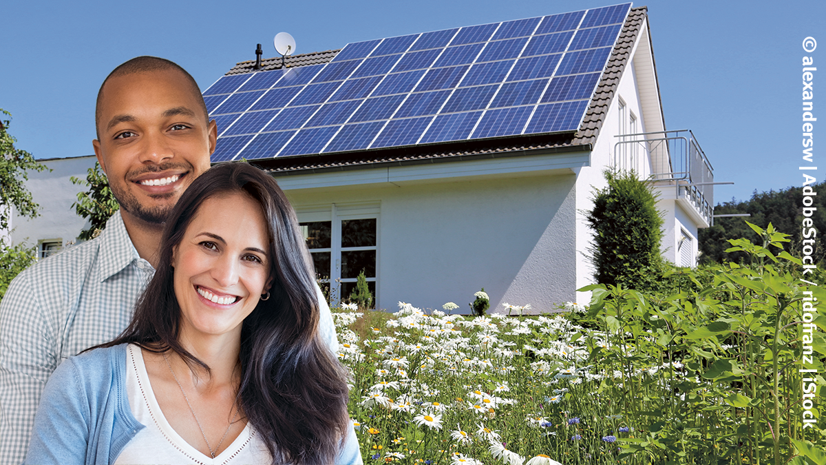 Zwei Menschen stehen vor einem Haus mit Photovoltaik auf dem Dach