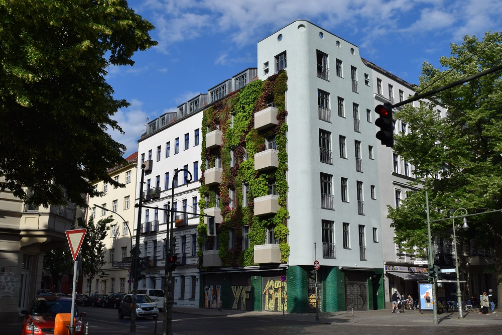 Mehrfamilienhaus in Berlin mit Fassadenbegrünung und Bäumen davor
