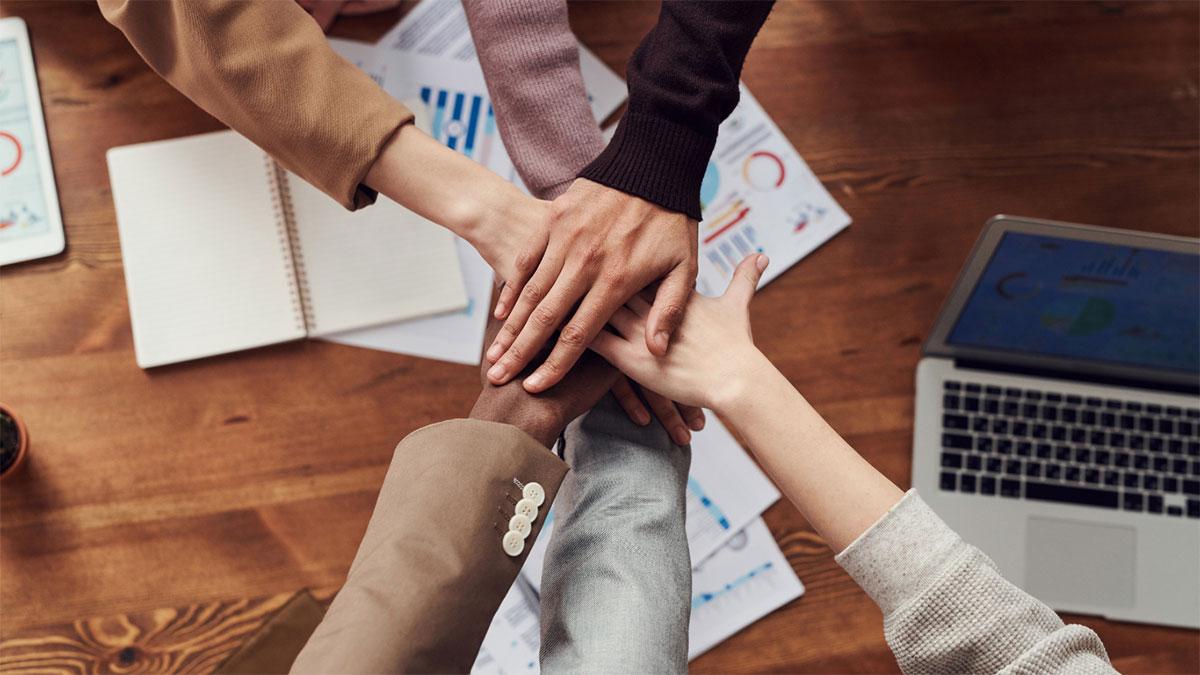 Menschen legen im Kreis ihre Hände übereinander