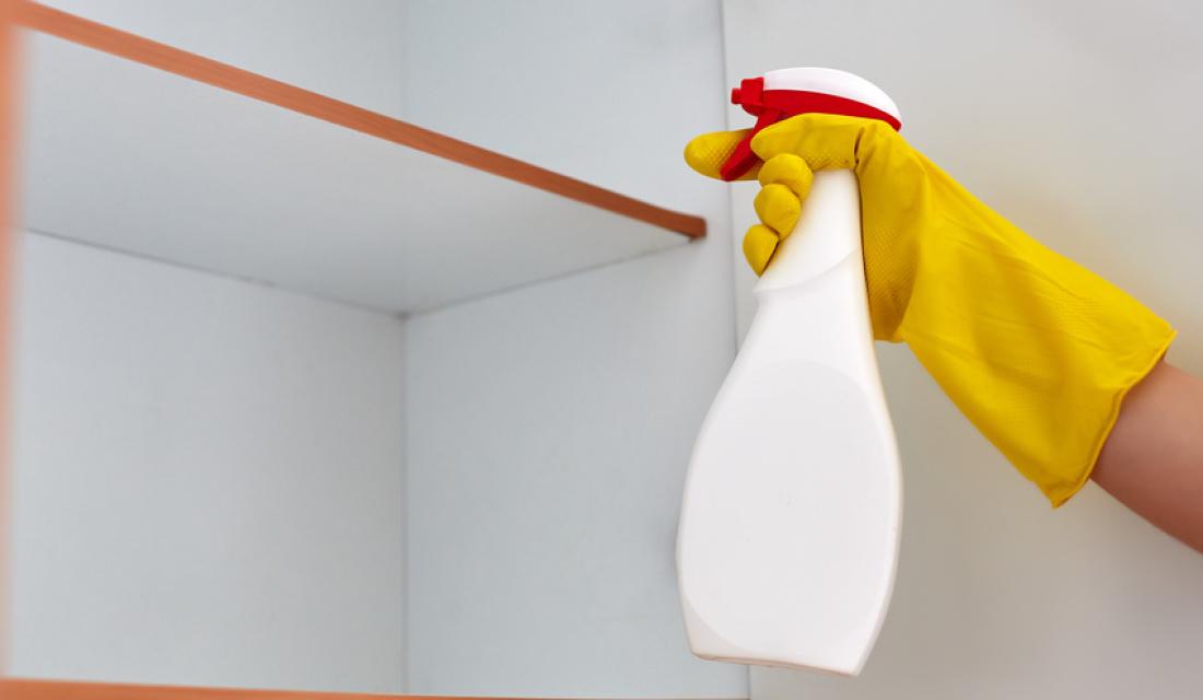 Jemand sprüht einen Küchenschrank ein