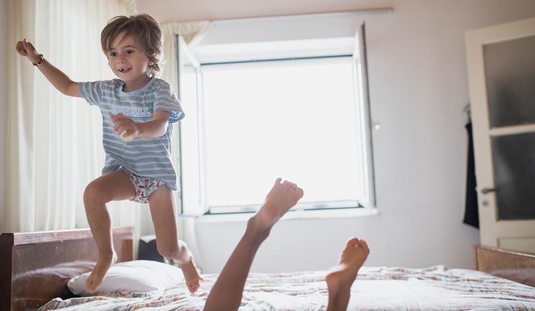 Junge springt auf einem Bett