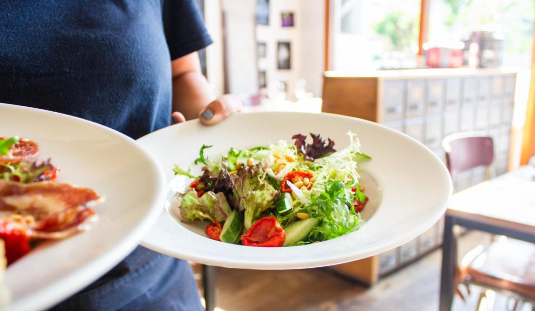 Eine Frau hält zwei Teller mit Salat