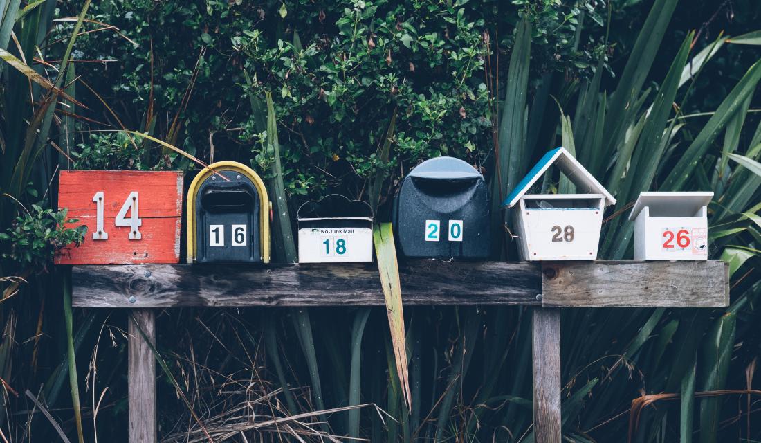 Briefkästen auf Zaun vor grünem, exotischen Garten