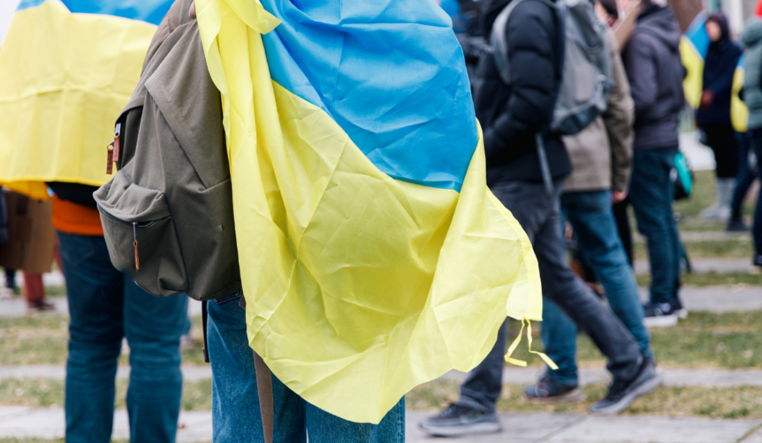 Mehrere Menschen stehen beieinander und tragen ukrainische Fahnen.