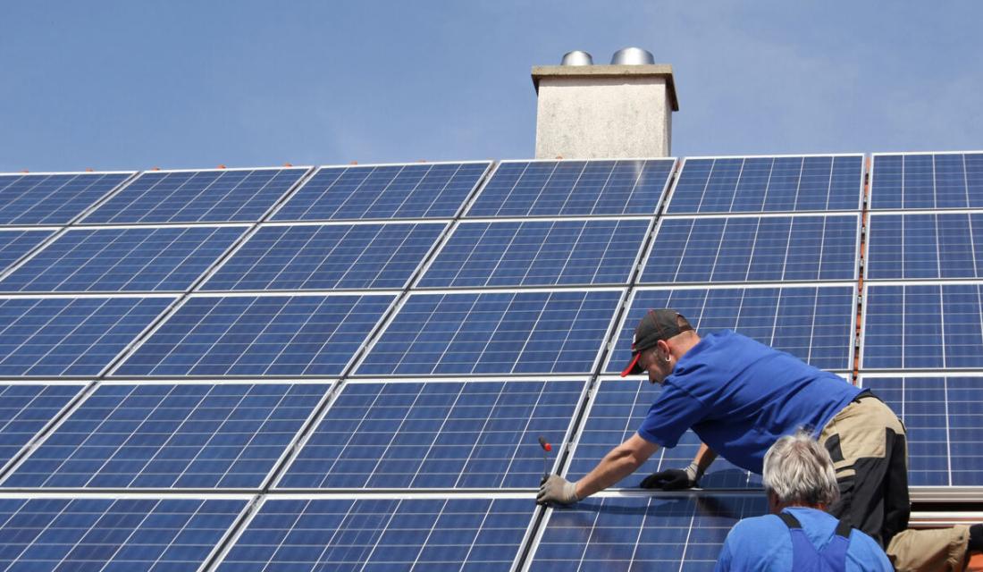 Blaue Solaranlage auf Dach und 2 Monteure