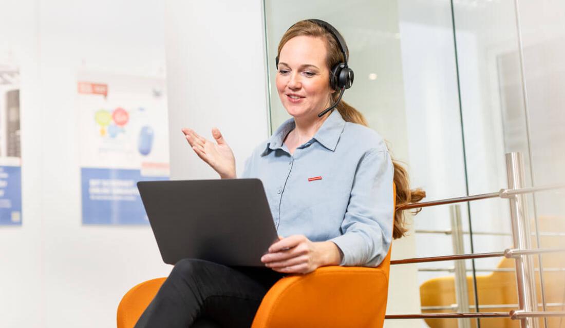 Frau sitzt telefonierend an einem Laptop