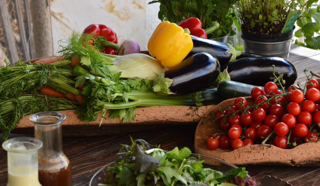 Auf einem Tisch liegen mehrere Gemüsesorten - Tomaten, Auberginen, Fenchel, Paprika, Sellerie