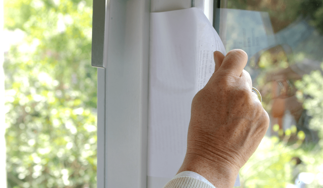 Hand zieht an Papier im Fensterrahmen