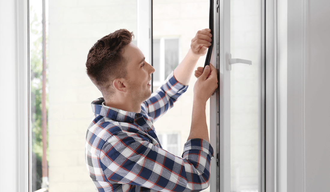 Mann bringt Dichtungsband an Fenster an