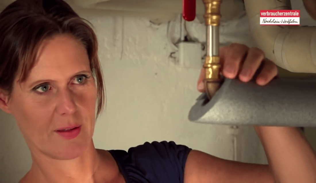 Frau dämmt Heizungsrohre im Keller