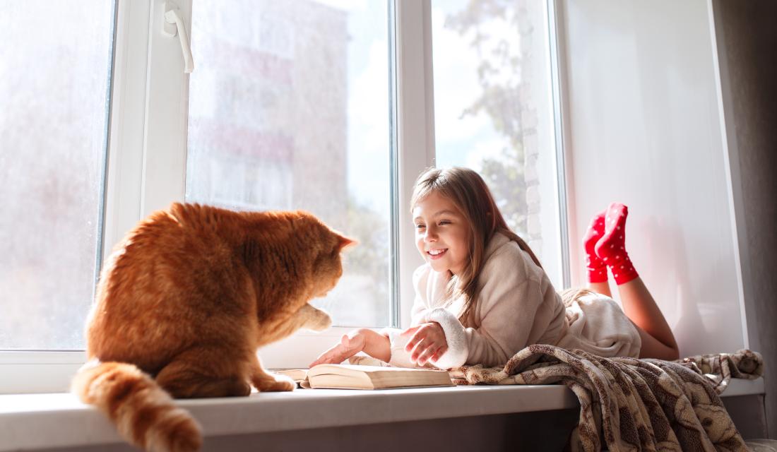 Mädchen mit Katze auf Fensterbank