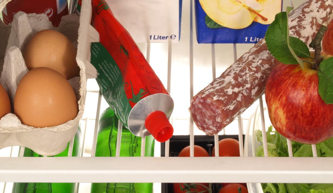 Ein geöffneter Kühlschrank mit Lebensmitteln wie Eiern, Salami, Tomatenmark