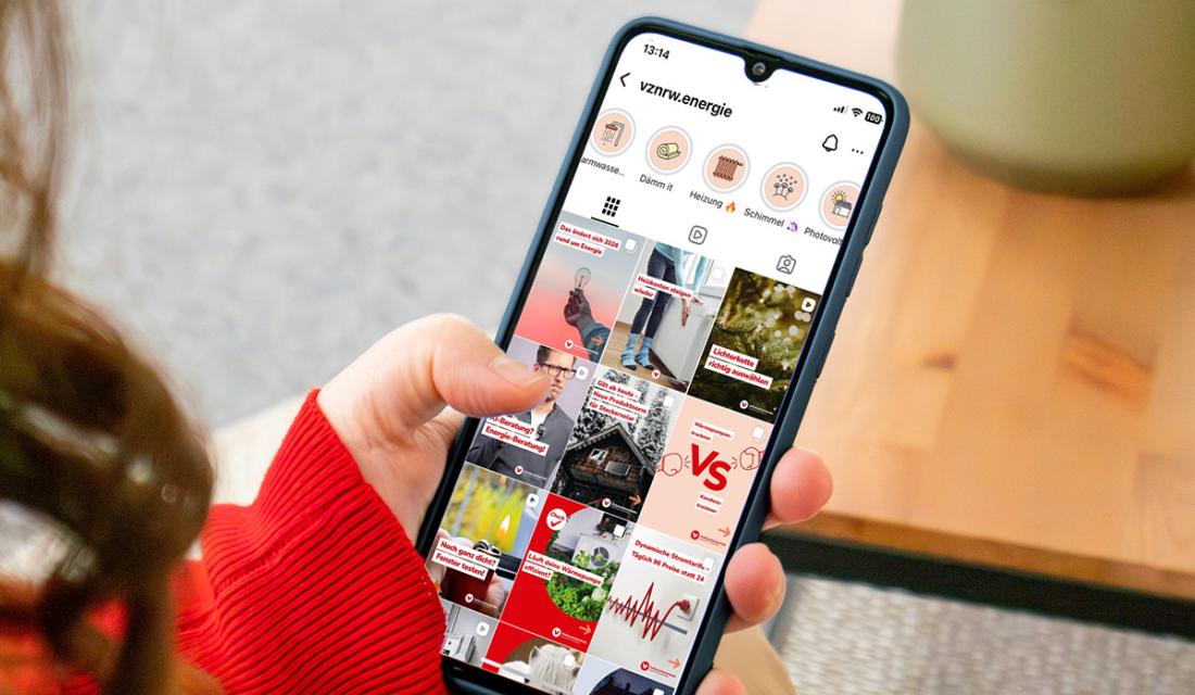 Eine Frau sitzt auf einer Couch und hält ein Smartphone in der Hand