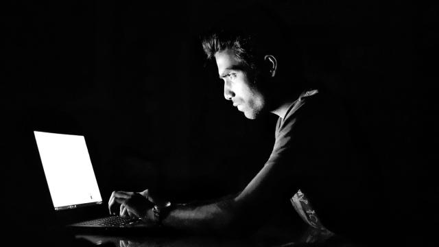 werbung bei safari ausschalten Düstere Schwarz-Weiß-Aufnahme eines Mannes, der vor einem Laptop sitzt