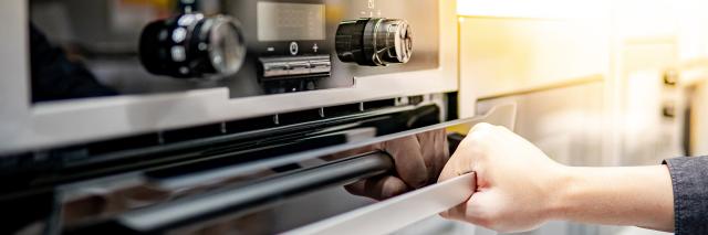 Eine Hand öffnet die Tür eines Backofens