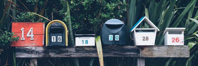 Briefkästen auf Zaun vor grünem, exotischen Garten