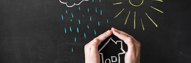 Hand schützt gezeichnetes Haus vor gezeichneten Regen- und Sonnenstrahlen