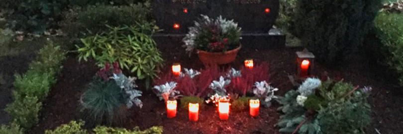 Grablicher und Pflanzen auf einem Grab in der Dämmerung