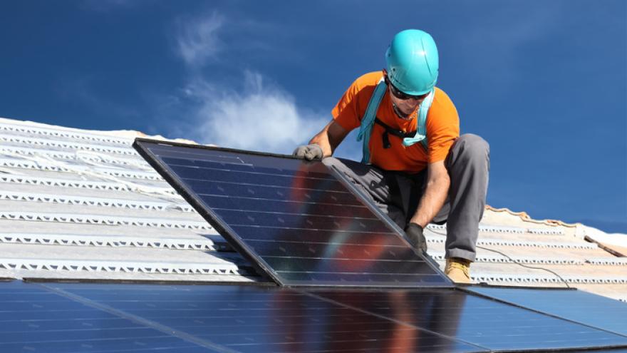 Mann montiert Solaranlage auf einem Dach