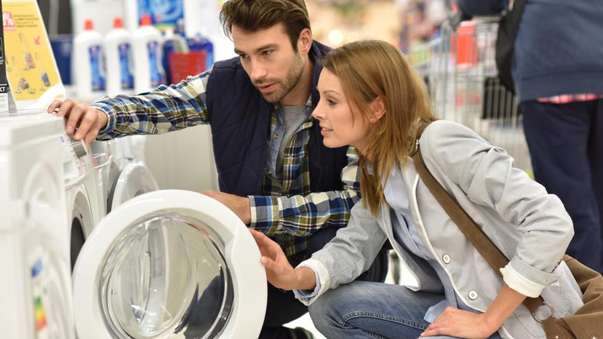 Verkaufssituation in einem Geschäft: zwei Menschen betrachten eine Waschmaschine.