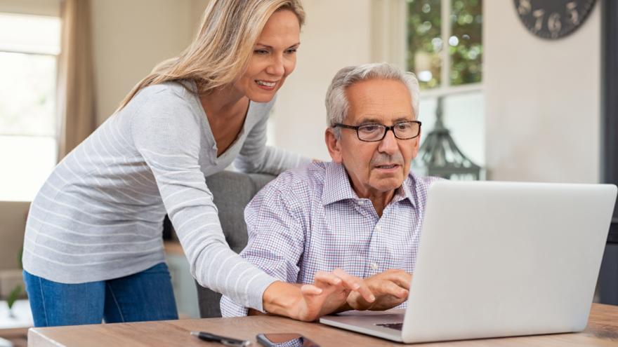 Eine Tochter hilft ihrem Vater bei der Benutzung eines Laptops