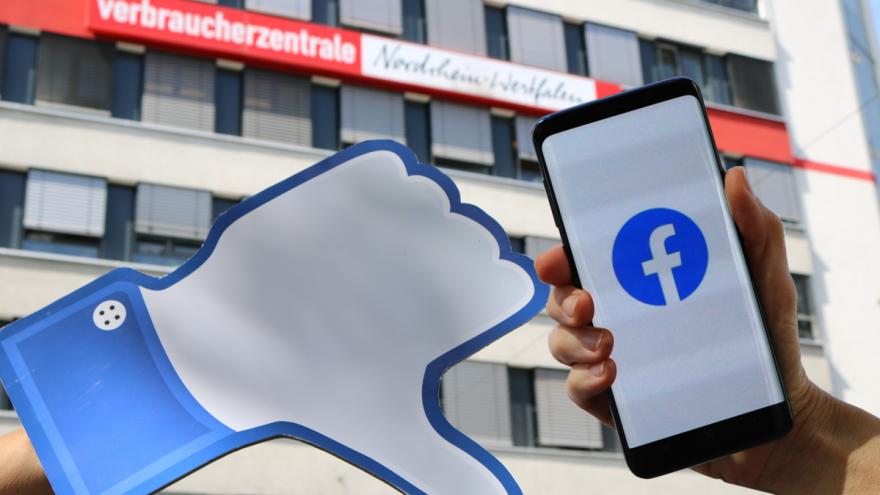 Daumen nach unten neben Smartphone mit Facebook-Logo vor der Geschäftsstelle der Verbraucherzentrale NRW in Düsseldorf
