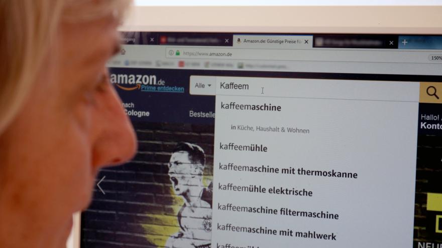 Frau sucht am PC auf der Seite von Amazon nach einer Kaffeemaschine.