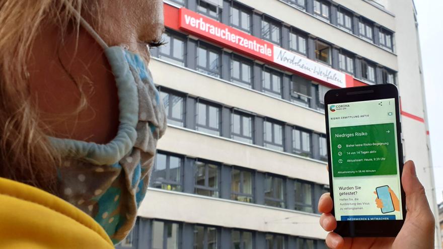 Frau hält Smartphone mit Corona-Warn-App in der Hand