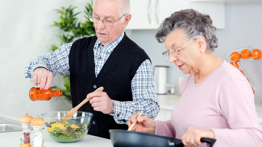 Senioren-Paar kocht gesundes Essen in der hellen Küche