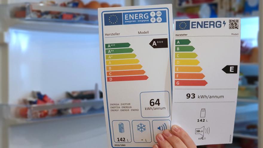 Zwei Energieeffizienzlabel vor einem offenen Kühlschrank