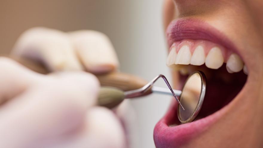 Zahnarzt untersucht die Zähne bei jemandem mit Spiegel