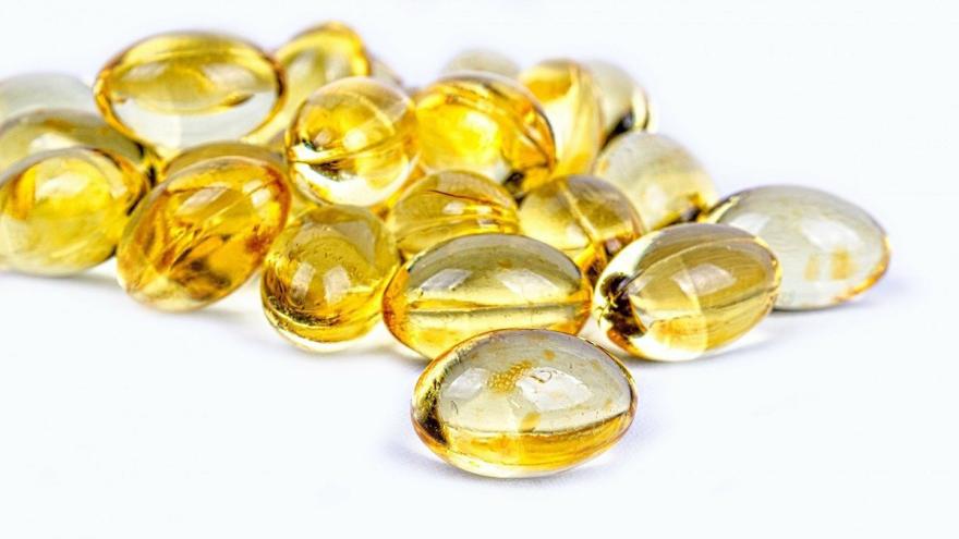 Mehrere gelbe transparente Pillen auf weißem Untergrund