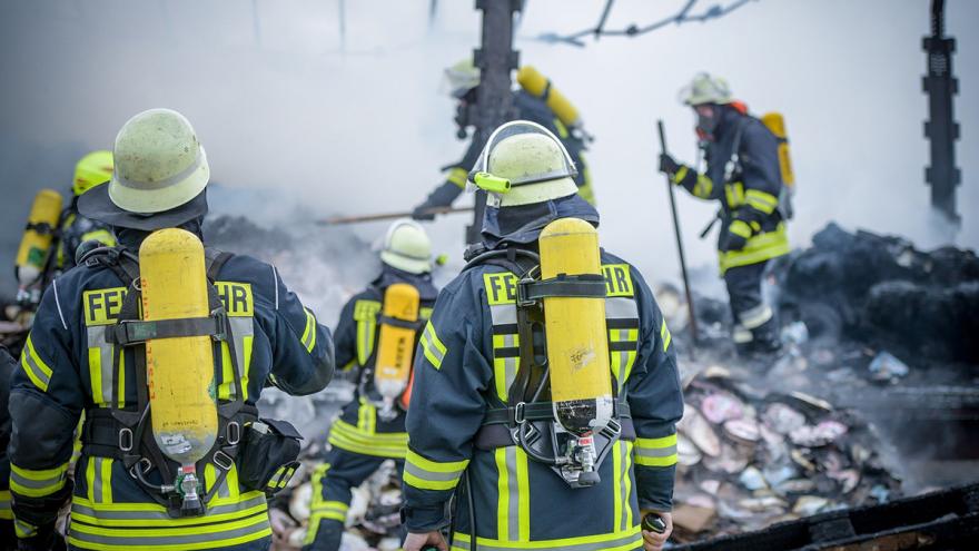 Feuerwehrleute vor und in einem abgebrannten Haus