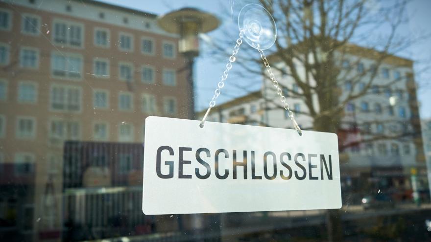 An der Fensterscheibe eines Geschäfts hängt das Schild "Geschlossen".