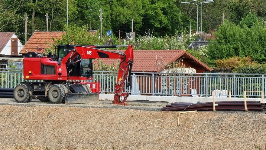 Roter Bagger auf einer Baustelle vor kleinen Häusern