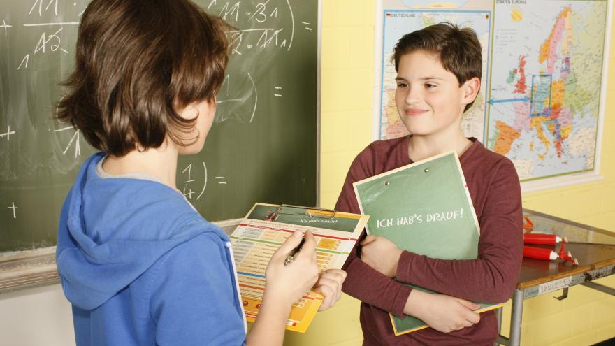 Zwei Kinder sprechen in der Schule miteinander.