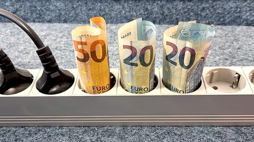 Geldscheine (50 und 20 Euro) stecken aufgerollt in drei Fächern einer Stromsteckerleiste
