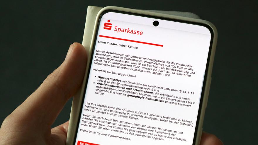 Hand hält Smartphone mit einer Phishing-Mail der Sparkasse auf dem Display