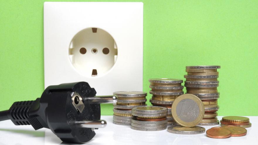 Stecker vor Steckdose und Münzgeld