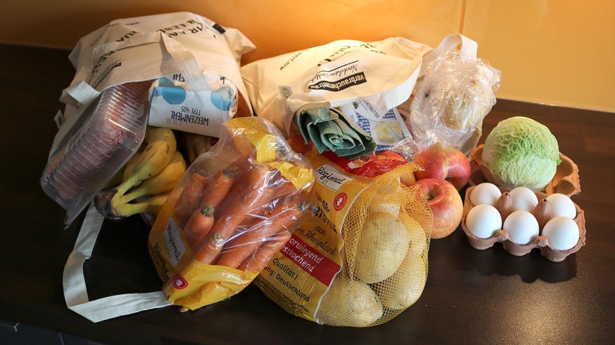 Zwei volle Einkaufsbeutel mit Lebensmitteln liegen auf einer Küchenarbeitsplatte.