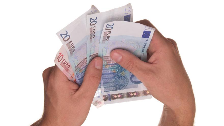 Zwei Hände halten 20- und 10-Euro-Scheine als Fächer
