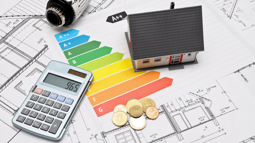 Bauplan mit Energieeffizienzskala, auf dem ein Häuschen und ein Taschenrechner stehen