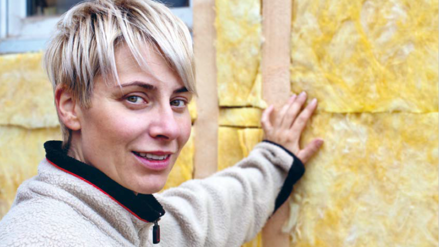 Frau lehnt sich an Wand, bei der die Dämmung zu sehen ist