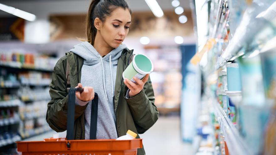 Eine junge Frau prüft beim Einkauf im Supermarkt ein Produkt