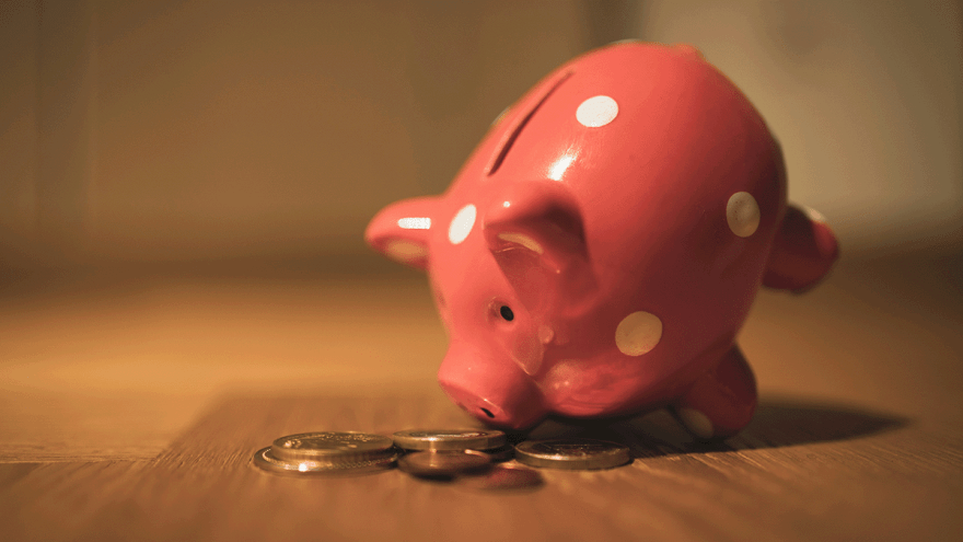 Sparschwein mit Münzen auf Holztisch
