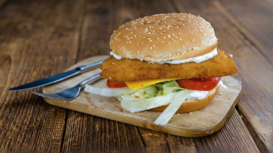 Ein Burgerbrötchen mit Fisch, Soße und Salat