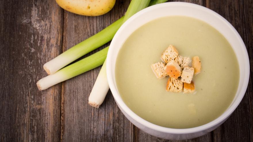 Einige Stangen Lauch und eine Schale mit Kartoffel-Gemüsesuppe