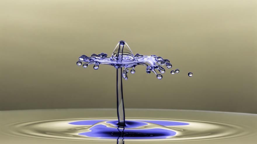 Aufnahme eines farbigen Tropfens, der auf klares Wasser trifft