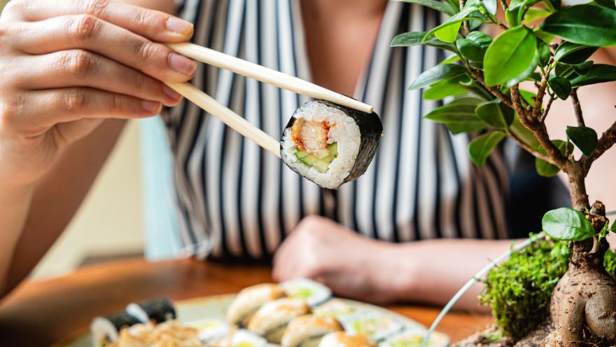 Eine Person isst Sushi mit Stäbchen